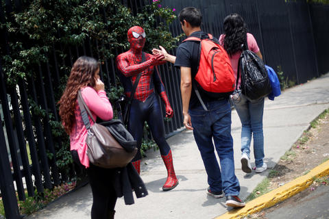 Moises Vazquez, 26, known as Spider-Moy, a computer science teaching assistant at the Faculty of Science of the National Autonomous University of Mexico (UNAM), who teaches dressed as a comic superhero Spider-Man, shakes hands with a student on his way to work in Mexico City, Mexico, May 27, 2016. REUTERS/Edgard Garrido SEARCH "SPIDERMAN TEACHER" FOR THIS STORY. SEARCH "THE WIDER IMAGE" FOR ALL STORIES - RTX2FIE0